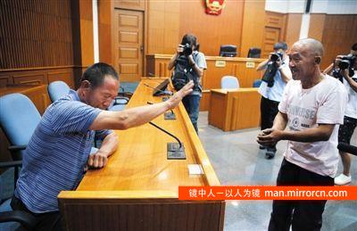 昨日庭审后，被告人尤洪湧的父亲（右）向受害人家属作揖道歉。